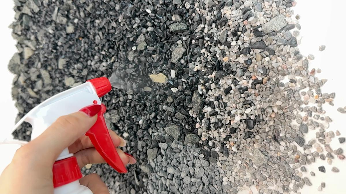 Spraying TerraTight Ease onto loose pebbles and gravel with a spray bottle